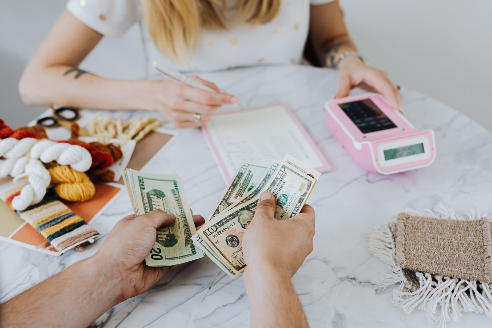Hands sorting a stack of cash beside a calculator for a savings plan