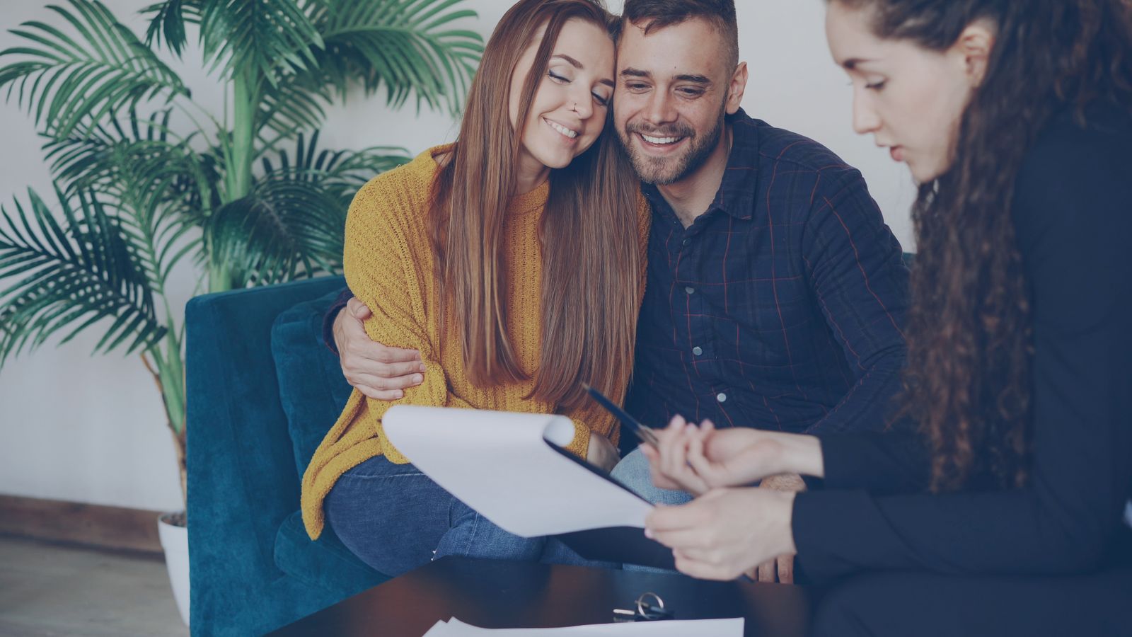 A couple reviewing life insurance documents with an adviser in a bright office